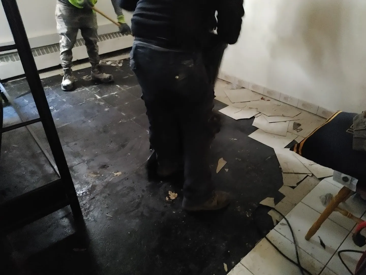 Technician assessing flooded commercial floor with water pooling and damaged materials removal